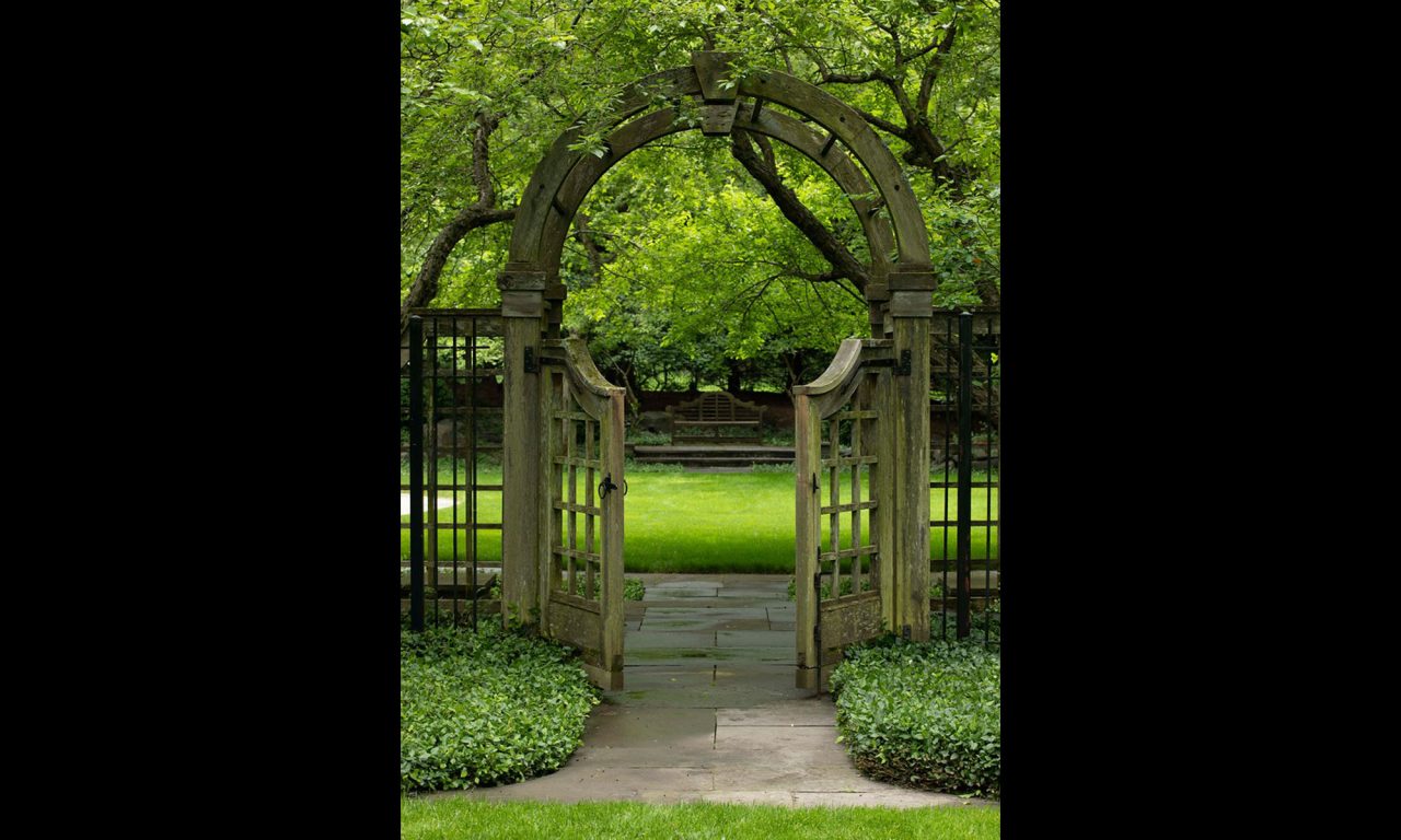 Arched wood arbor with English lattice gates and a bluestone walk.