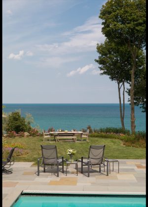 Serene view to Lake Michigan looking over a grass lawn with outdoor dining furniture.