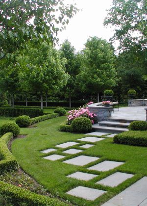 Bluestone steppers on a gravel path through a landscaped side yard along an Arborvitae hedge.