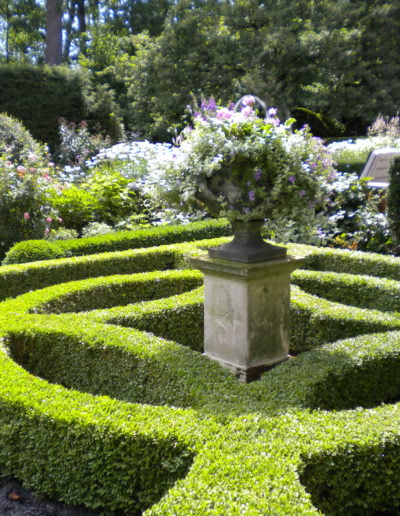 Parterre de boj en el jardín de plantas perennes, con una urna de plomo sobre un pedestal de piedra caliza