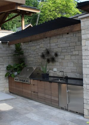 Outdoor kitchen and grill with granite countertop embedded in stone wall