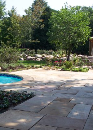 Crab orchard stone pool deck featuring wood pergola