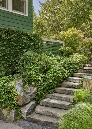 New York fieldstone steps blend seamlessly into the landscape, providing access from the lower garage to the upper terrace.