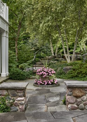 Stone entrance feature planted urn, flagstone steps, and natural border